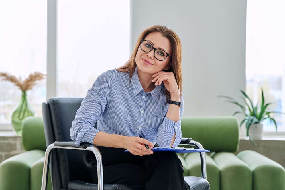 Portrait,Of,Professional,Psychologist,Therapist,Woman,With,Clipboard,In,Office woman-desk-online-group-hypnosis-meeting